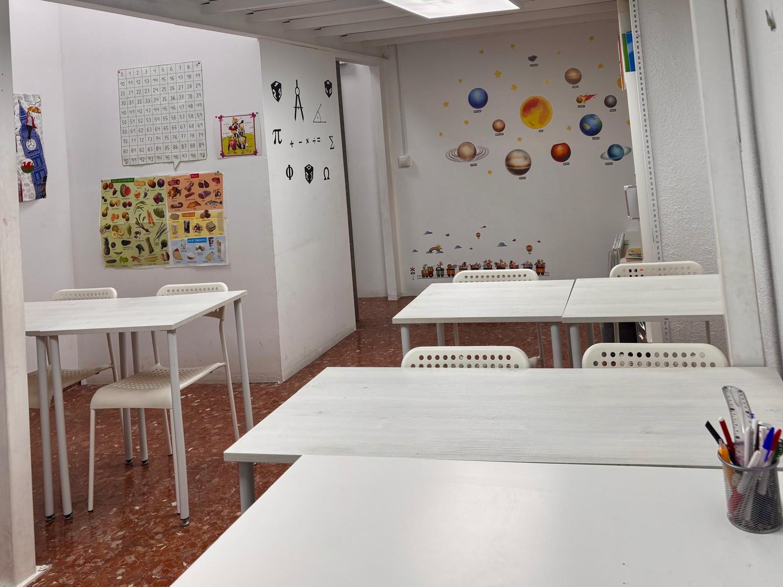 Sala de estudios con mesas y sillas blancas